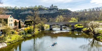 Flusslandschaft mit Ruderboot, Brücke und Anwesen unter einer Burgruine.