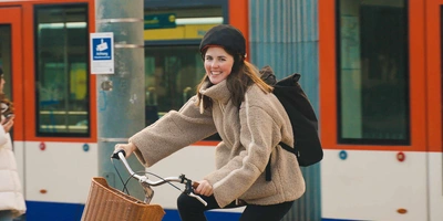 Frau auf Fahrrad fährt neben Zug.