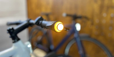 Nahaufnahme eines Fahrradlenkers mit einem leuchtenden gelben Lenkerlicht