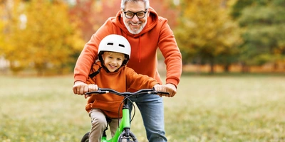 Ein Mann bringt einem Kind das Fahrradfahren bei