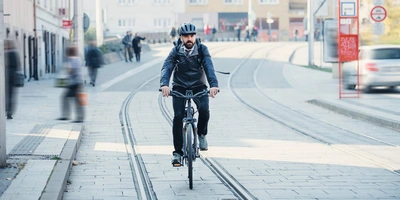 Mann mit Helm fährt durch Stadtmitte.