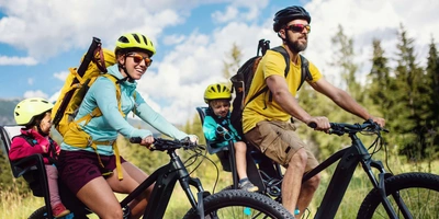Zwei Personen fahren mit ihren Kindern sitzend im Fahrradsitz Fahrrad
