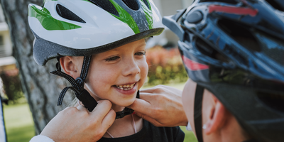 Eine Mutter hilft ihrem Sohn dabei seinen Fahrradhelm zu schließen