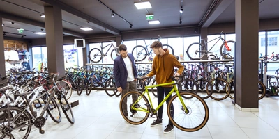 Zwei Männer in einem Fahrradgeschäft, einer hält ein grünes Fahrrad.