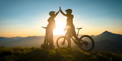 Zwei Frauen schlagen ein im Sonnenuntergang auf dem Fahrrad in den Bergen