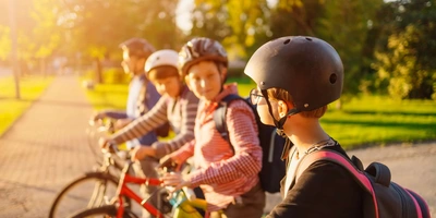Fünf Kinder auf Fahrrädern in einem sonnigen Park, bereit zum Fahren