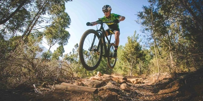 Crossbike vs. Mountainbike: Welches passt zu dir? Mountainbiker springt mit Mountainbike durch den Wald