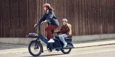 Lastenräder können den Alltag enorm erleichtern Frau befördert Kind auf Multitinker Lastenrad