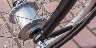 Nahaufnahme des Fahrradnaben mit Speichen, Achse und Nabendynamo auf einem Pflastersteinboden.