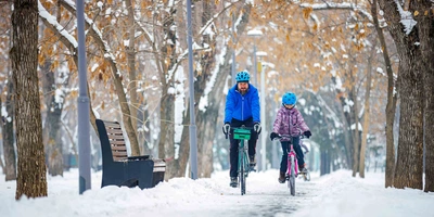 Mann und Kind fahren Fahrrad im Schnee.