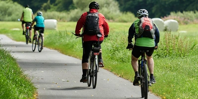 Vier Fahrradfahrende von hinten, die einen Fahrradweg entlangfahren