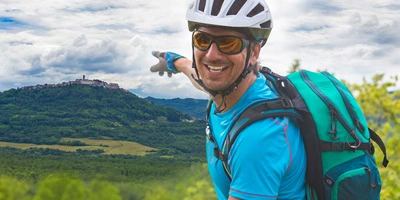 Mann fährt mit Fahrrad durch Slowenien und zeigt auf Landschaft