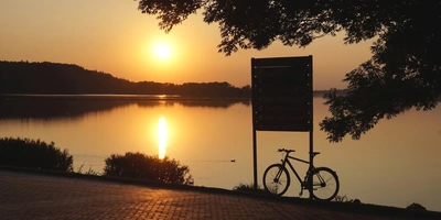 Fahrrad ohne Ständer abstellen: Mit dem praktischen und leichten Fahrrad-Anker bist du flexibel und dein Bike steht stabil Blick auf einen See bei Sonnenuntergang Silhouette von Bäumen Schild Fahrrad Spielgelung Reflektion der Sonne auf dem See