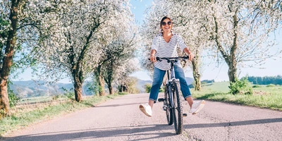 Frau fährt lachend auf dem Fahrrad im Frühling