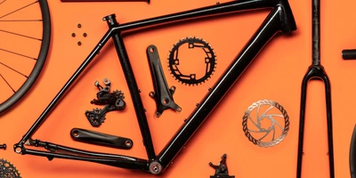 Rahmenarten Fahrrad: Diese Fahrrad Rahmenarten gibt es Schwarzer Fahrradrahmen und Teile auf orangefarbenem Hintergrund.