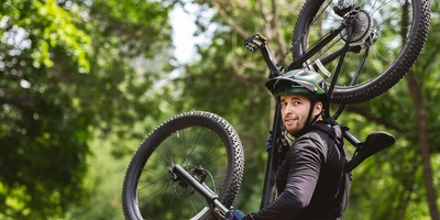 Auch im Gelände ist der Schutz vor Kratzern praktisch Mann trägt Mountainbike auf Schulter