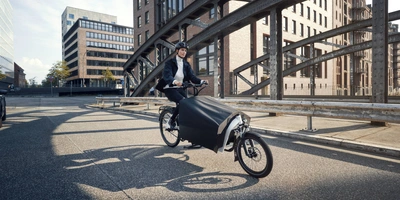 Mann fährt auf einem E- Lastenrad 65 durch die Stadt