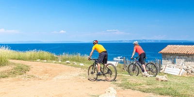 Zwei Personen fahren am Strand Fahrrad