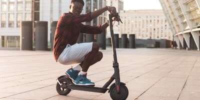 Mann fährt auf E-Scooter in der Hocke
