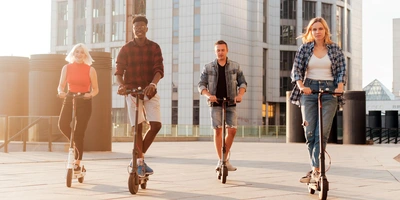 eine Gruppe von 4 Menschen fährt gemeinsam auf E-Scootern