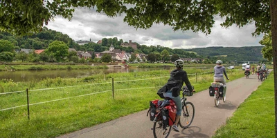 Fahrradfahrer fahren in Gruppe an Fluss vorbei