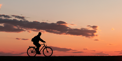 Silhouette einnes Mannes auf einem Fahrrad im Sonnenuntergang.