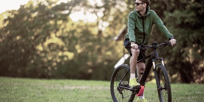 Mann steht mit Fahrrad auf einer Wiese