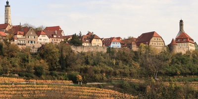 Blick auf eine malerische Stadt mit historischen Gebäuden und sanften Hügeln.