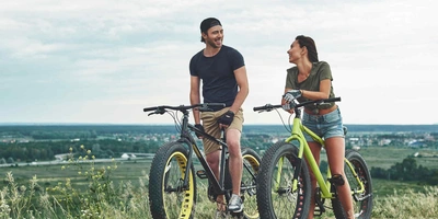 Mann und Frau auf Fatbike auf Wiese.