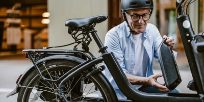 Was hat es mit Urban E-Bikes auf sich? Mann in der Stadt nimmt Akku aus seinem E-Bike raus