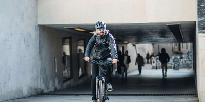Mann mit Helm fährt mit E-Bike durch Stadt.