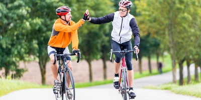Zwei Rennradfahrer klatschen sich am Ziel ab.