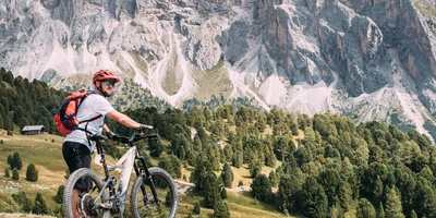 Person hält ein E-Bike auf einem Berg fest