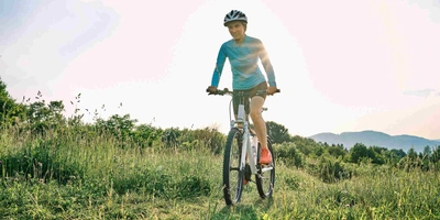 Waldbike baut umweltfreundliche Elektrofahrräder. Frau fährt mit Mountainbike über Wiese.