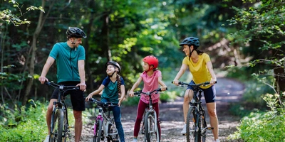 Familie mit Kindern steht mit Fahrrädern im Wald.