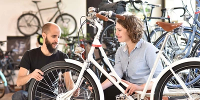 Eine Frau wird im Fahrradladen von einem Händler beraten.