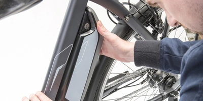 Mann betrachtet Akku eines E-Bikes