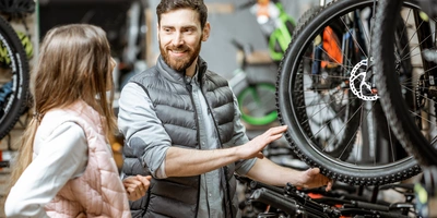 Fahrradverkäufer berät eine junge Frau in einem Fahrradladen