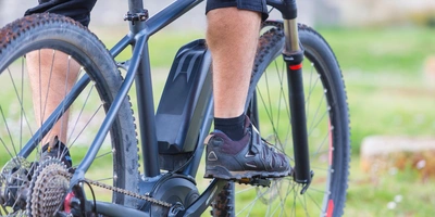 Yamaha Motor Mann auf einem Mountainbike mit Yamaha Motor der mit dem linken Fuß die Pedale tritt