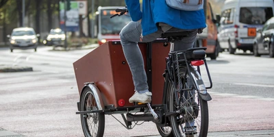 Person fährt auf einem Lastenfahrrad entlang einer Stadtstraße