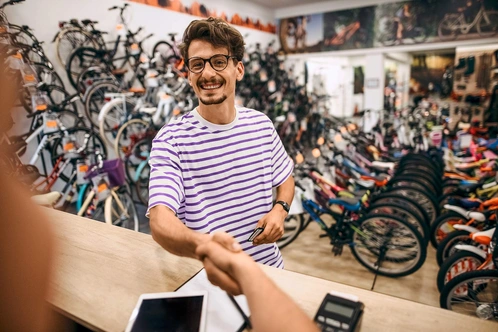 Kunde im Fahrradfachhandel schüttelt Hand von Verkäufer