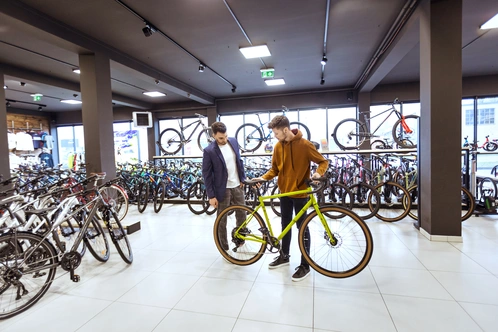 Zwei Männer stehen in einem Fahrradgeschäft und betrachten ein grünes Fahrrad.