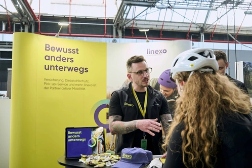 Eine Person spricht mit einer Fahrradhelm-tragenden Person an einem Informationsstand