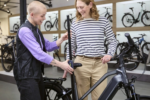 Zwei Personen in einem Fahrradgeschäft, eine zeigt der anderen ein E-Bike.