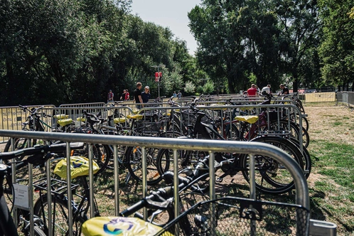Ein Fahrradparkplatz mit mehreren Fahrrädern und Grünflächen im Hintergrund.