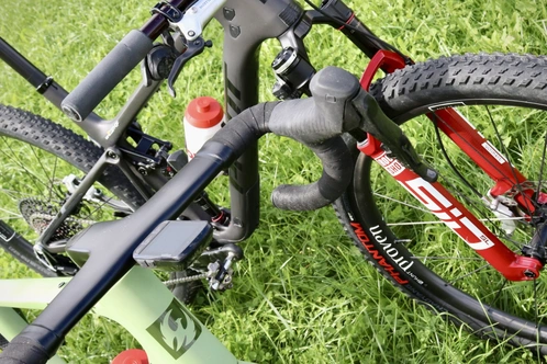 Zwei Fahrräder liegen auf grünem Gras, eines schwarz und rot, das andere grün.