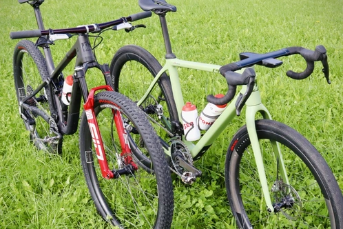 Zwei Fahrräder in einer grünen Wiese, eines schwarz und eines grün-rot.