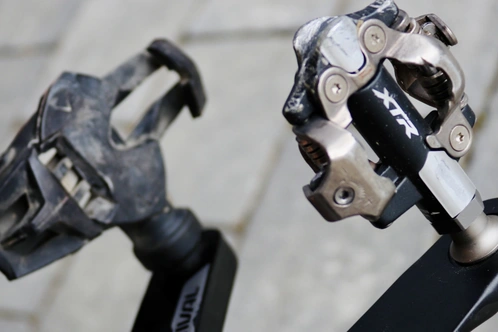 Zwei Fahrradpedale, ein schmutzig und abgenutzt, das andere neu und glänzend.